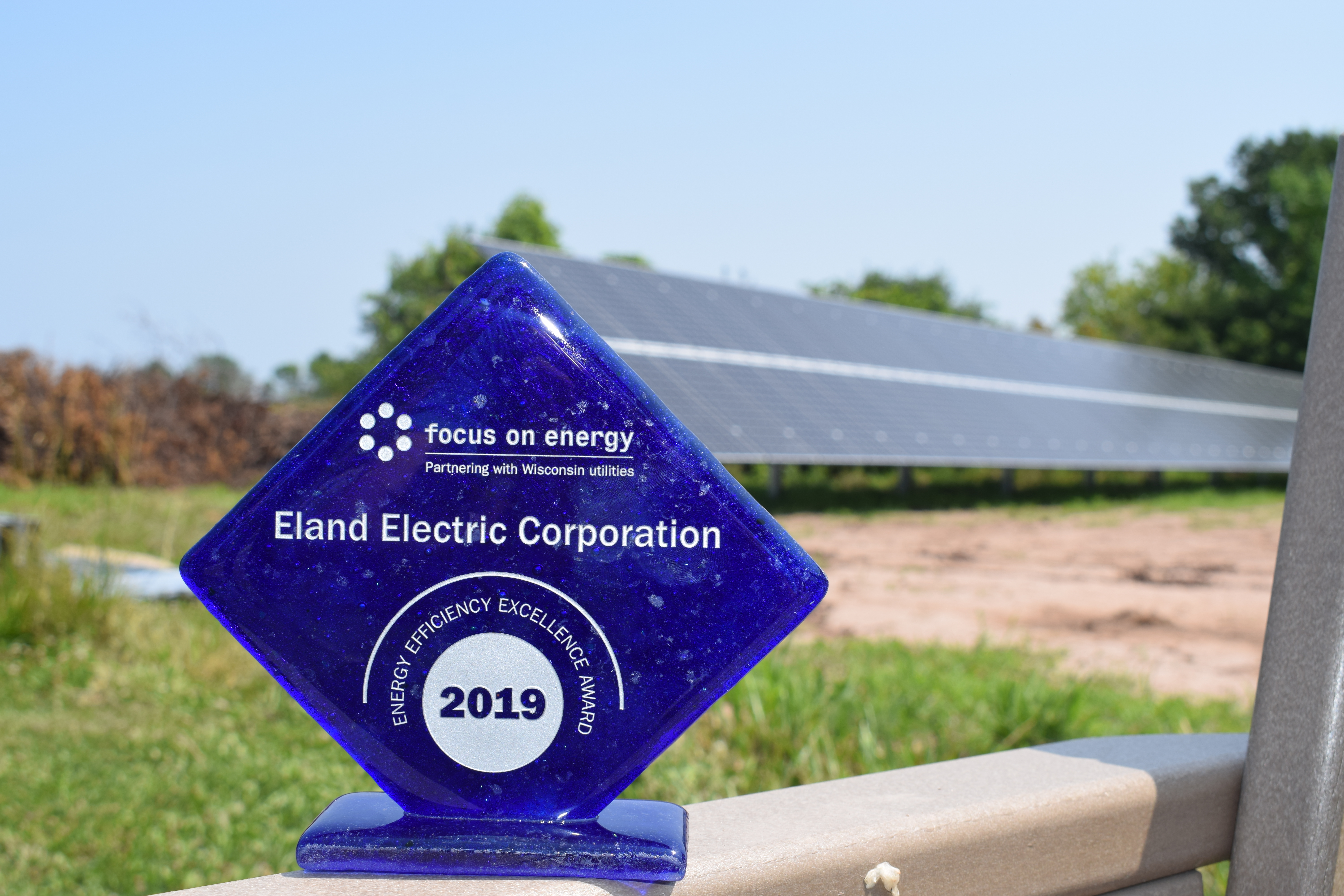 A blue award sits on a ledge. In the background, you can see green space and a solar panel array.